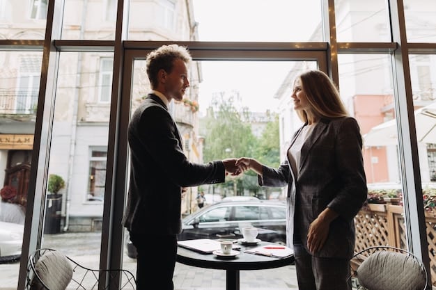 Two people shaking hands over a cafe table with a contract and coffee, symbolizing a successful business agreement and client acquisition.