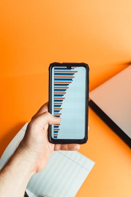 A person's hand holding a smartphone displaying an analytical graph showing upward financial growth, with a blurred background of a laptop and notebook, symbolizing passive income generation and smart investing.
